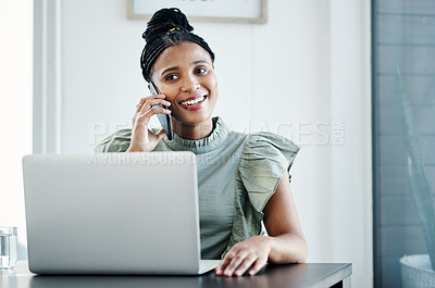 Buy stock photo Shot of an attractive young businesswoman sitting in the office and using her laptop while talking on her cellphone
