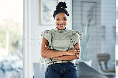 Buy stock photo Shot of an attractive young businesswoman standing alone in the office with her arms folded during the day