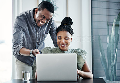 Buy stock photo Shot of two young businesspeople having a discussion in the office while using a laptop
