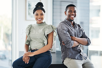 Buy stock photo Shot of two young businesspeople sitting together in the office during the day