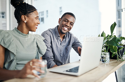 Buy stock photo Shot of two young businesspeople sitting together and having a discussion in the office while using a laptop