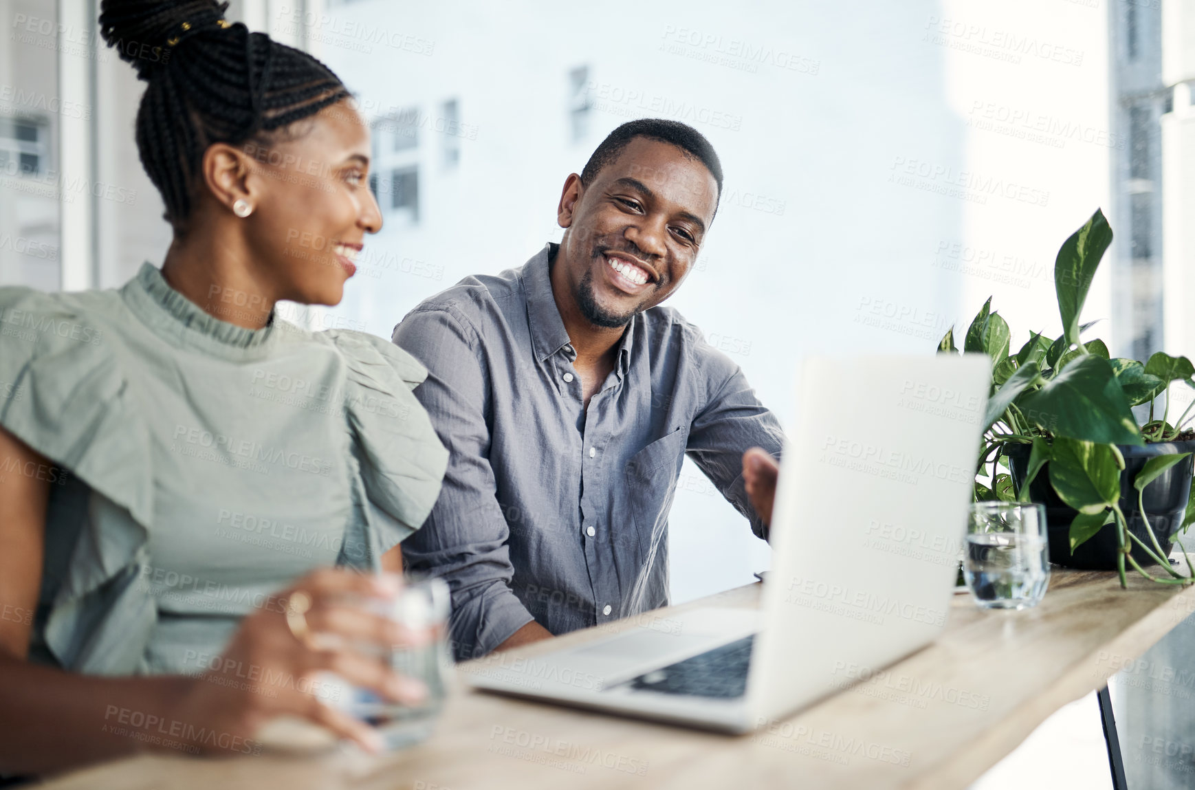 Buy stock photo Shot of two young businesspeople sitting together and having a discussion in the office while using a laptop