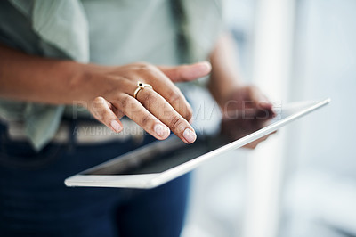 Buy stock photo Cropped shot of an unrecognizable businesswoman standing alone in her office and using a digital tablet