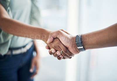 Buy stock photo Cropped shot of two unrecognizable businesspeople standing in the office together and shaking hands in agreement