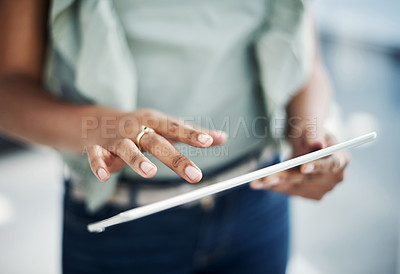 Buy stock photo Cropped shot of an unrecognizable businesswoman standing alone in her office and using a digital tablet