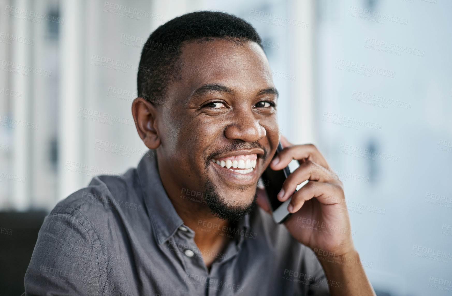 Buy stock photo Shot of a handsome young businessman sitting alone in his office and using his cellphone