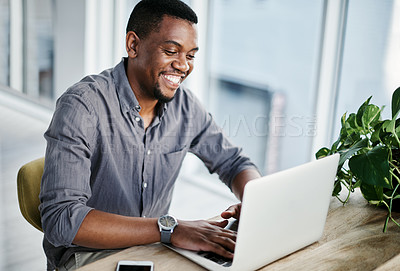 Buy stock photo Shot of a handsome young businessman sitting alone in his office and using his laptop