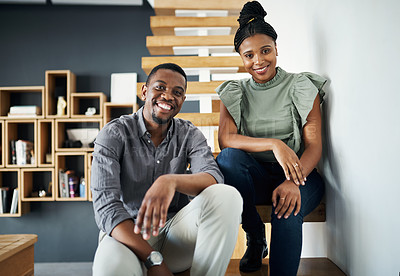 Buy stock photo Shot of two young businesspeople sitting together on a staircase in the office during the day