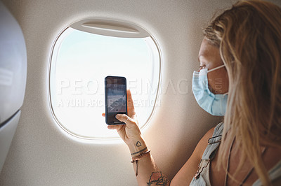 Buy stock photo Shot of  a young woman taking a photo of the view from her window seat in the aeroplane