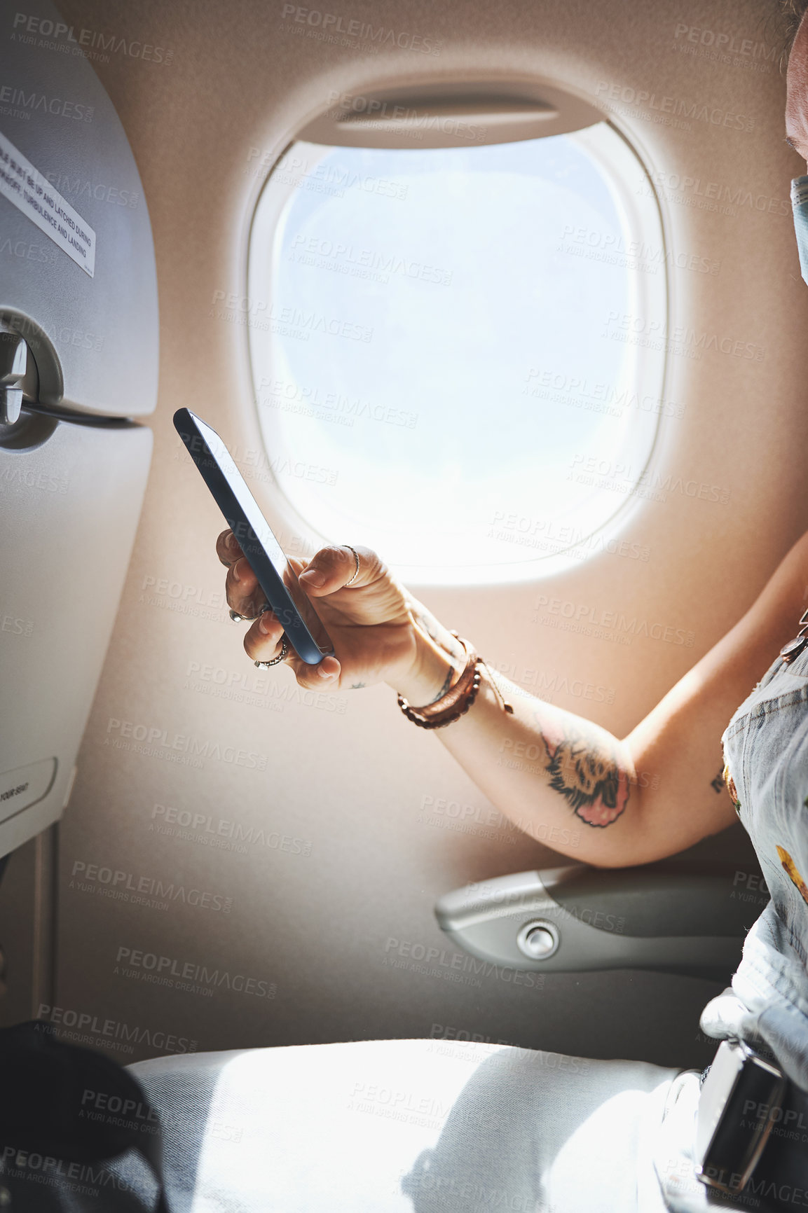 Buy stock photo Cropped shot of a woman using her phone in the aeroplane