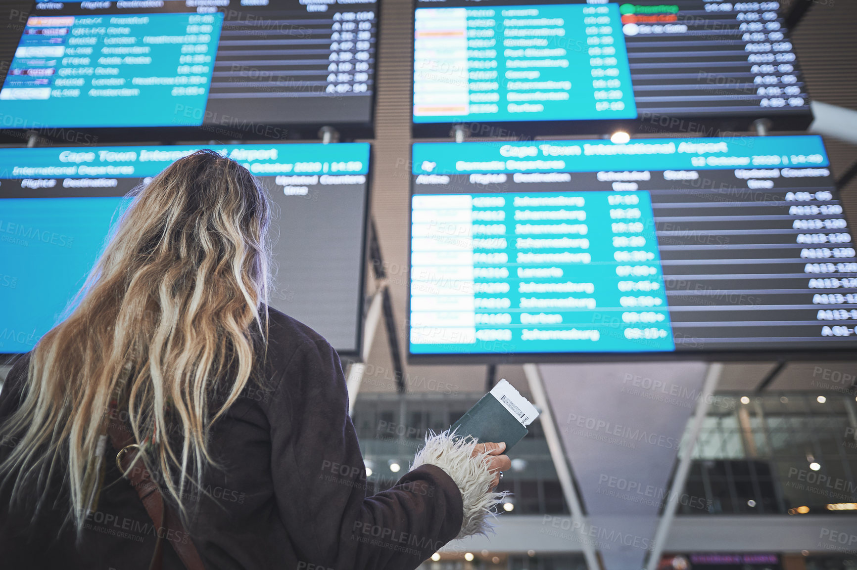 Buy stock photo Shot of a woman checking the time of her flight at the airport