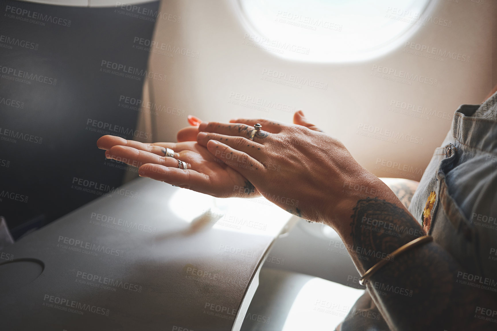 Buy stock photo Cropped shot of a woman sanitising her hands in the aeroplane