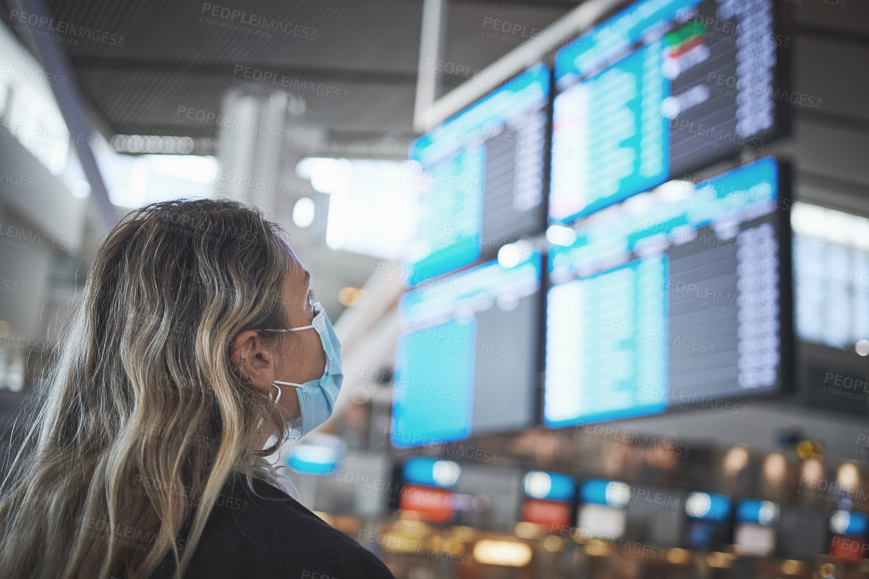 Buy stock photo Shot of a woman checking the time of her flight at the airport