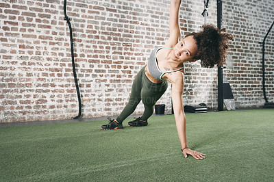 Buy stock photo Shot of a sporty young woman doing the side plank at the gym