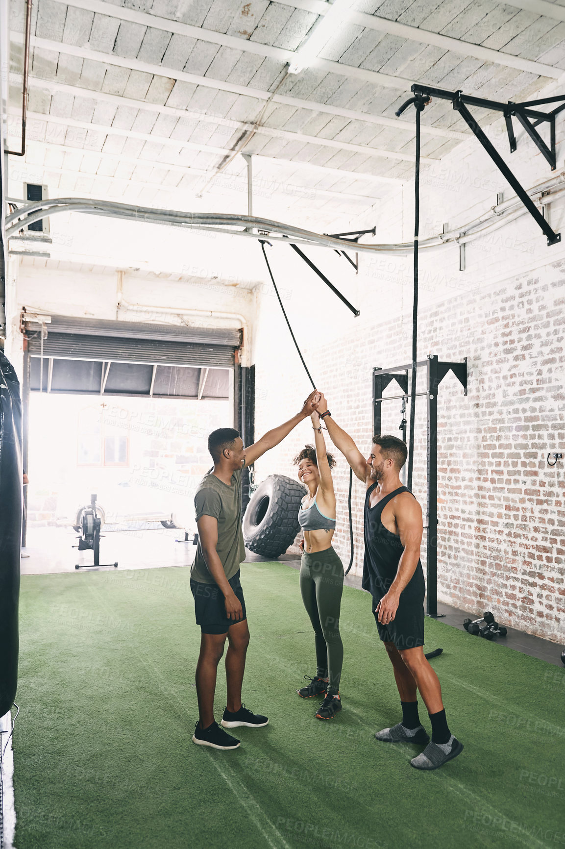 Buy stock photo Shot of three sporty young people giving each other a high five