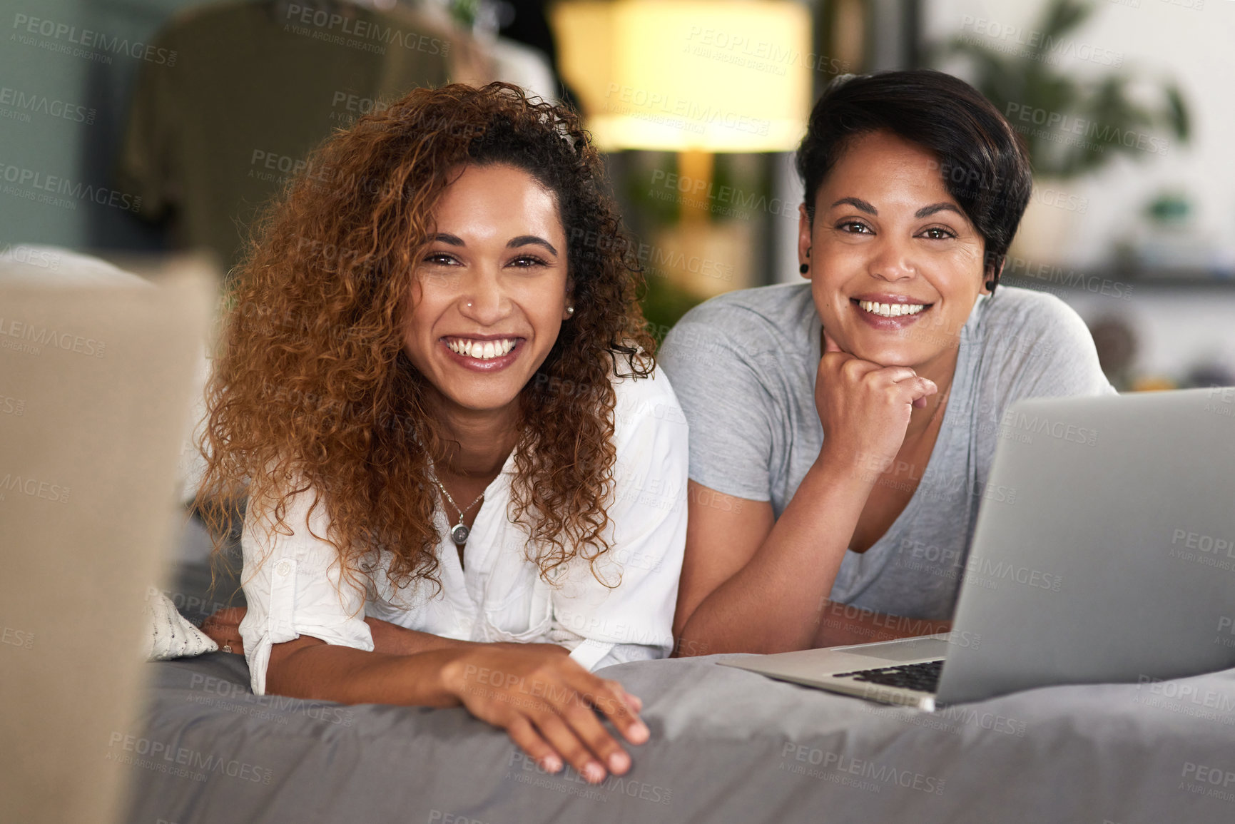 Buy stock photo Shot of a young couple using a laptop while lying on their bed