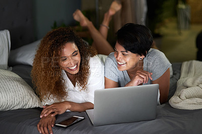 Buy stock photo Shot of a young couple using a laptop while lying on their bed