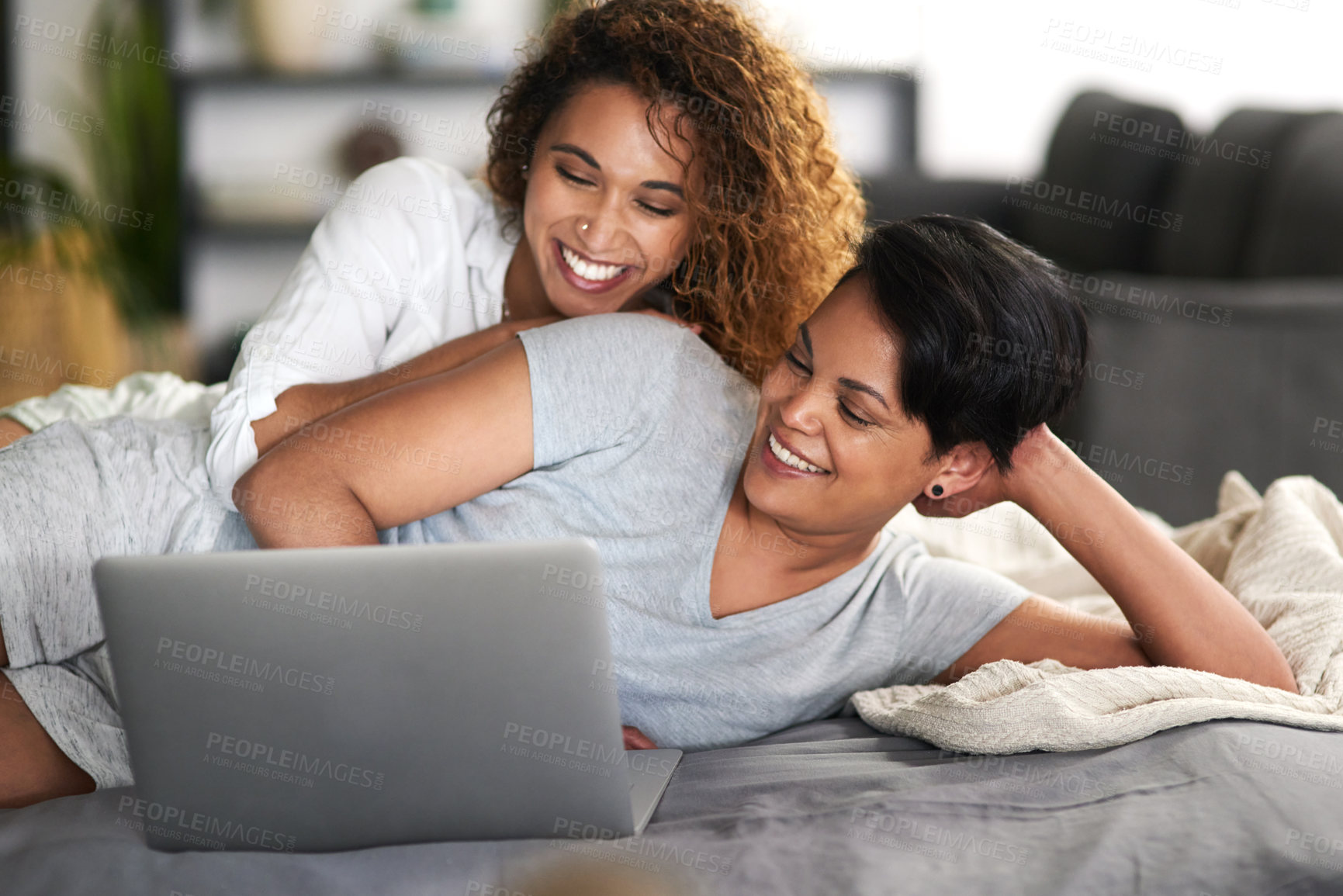 Buy stock photo Shot of a young couple using a laptop while lying on their bed