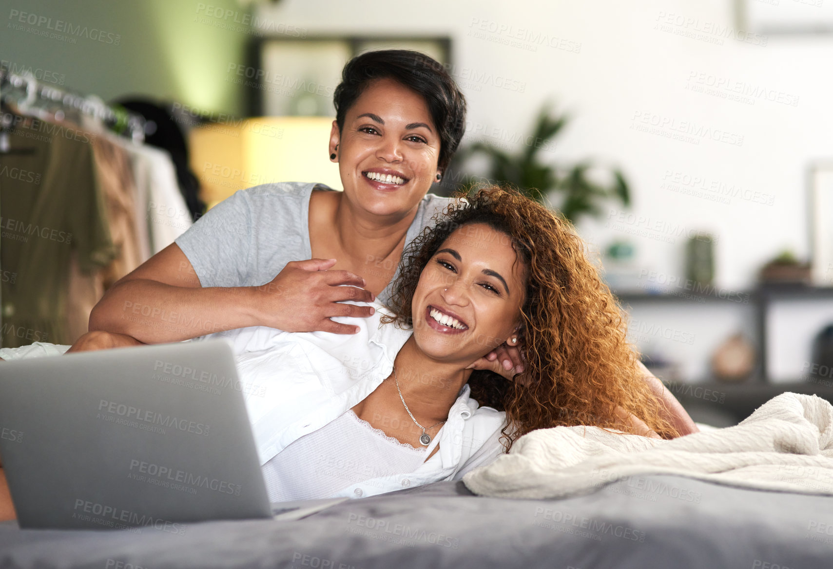 Buy stock photo Shot of a young couple using a laptop while lying on their bed