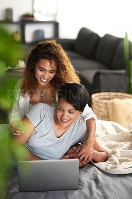 Buy stock photo Shot of a young couple using a laptop while lying on their bed