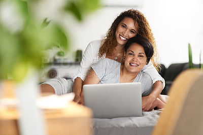 Buy stock photo Shot of a young couple using a laptop while lying on their bed