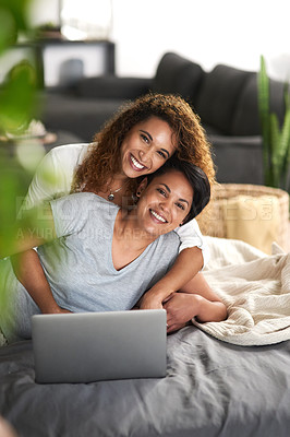 Buy stock photo Shot of a young couple using a laptop while lying on their bed