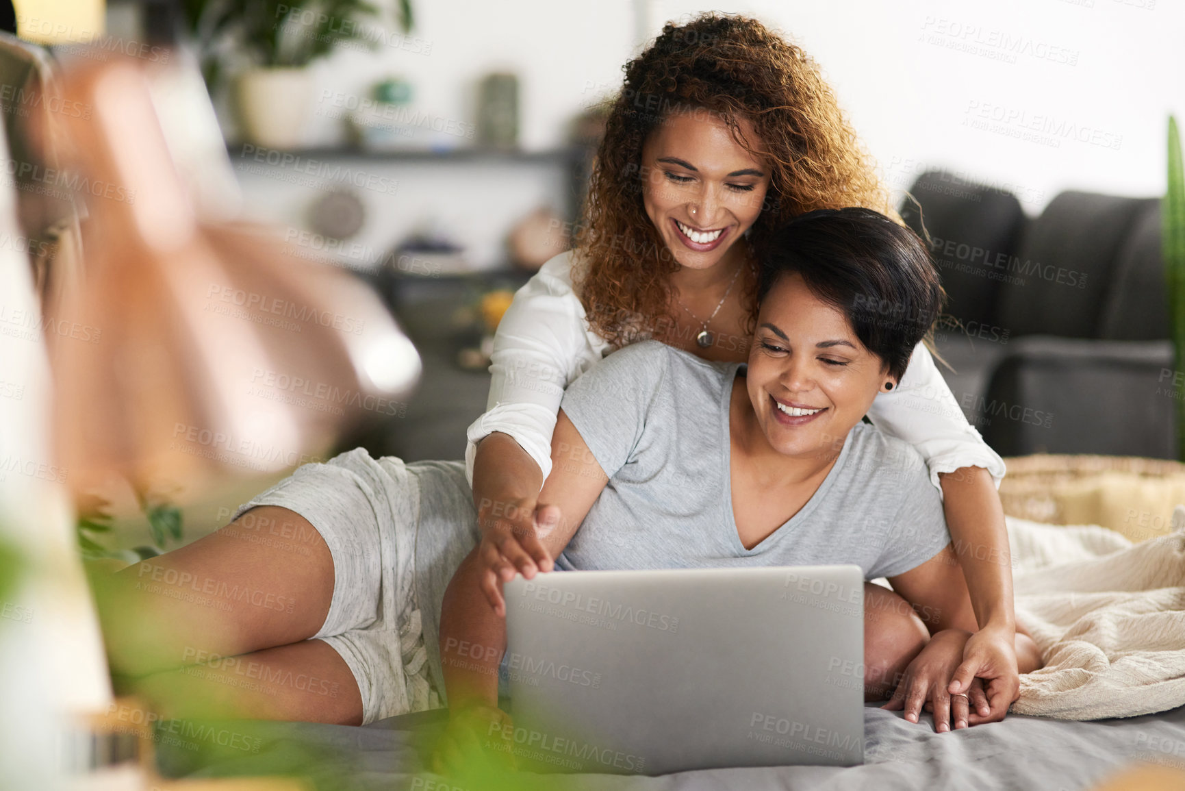 Buy stock photo Shot of a young couple using a laptop while lying on their bed