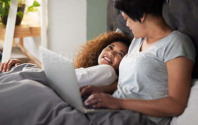 Buy stock photo Shot of a woman using her laptop while lying in bed with her partner