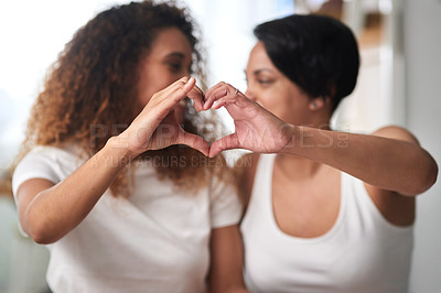 Buy stock photo Shot of an affectionate couple sitting together and forming a heart shape with their hands