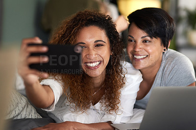 Buy stock photo Shot of an affectionate couple taking a selfie while lying on their bed