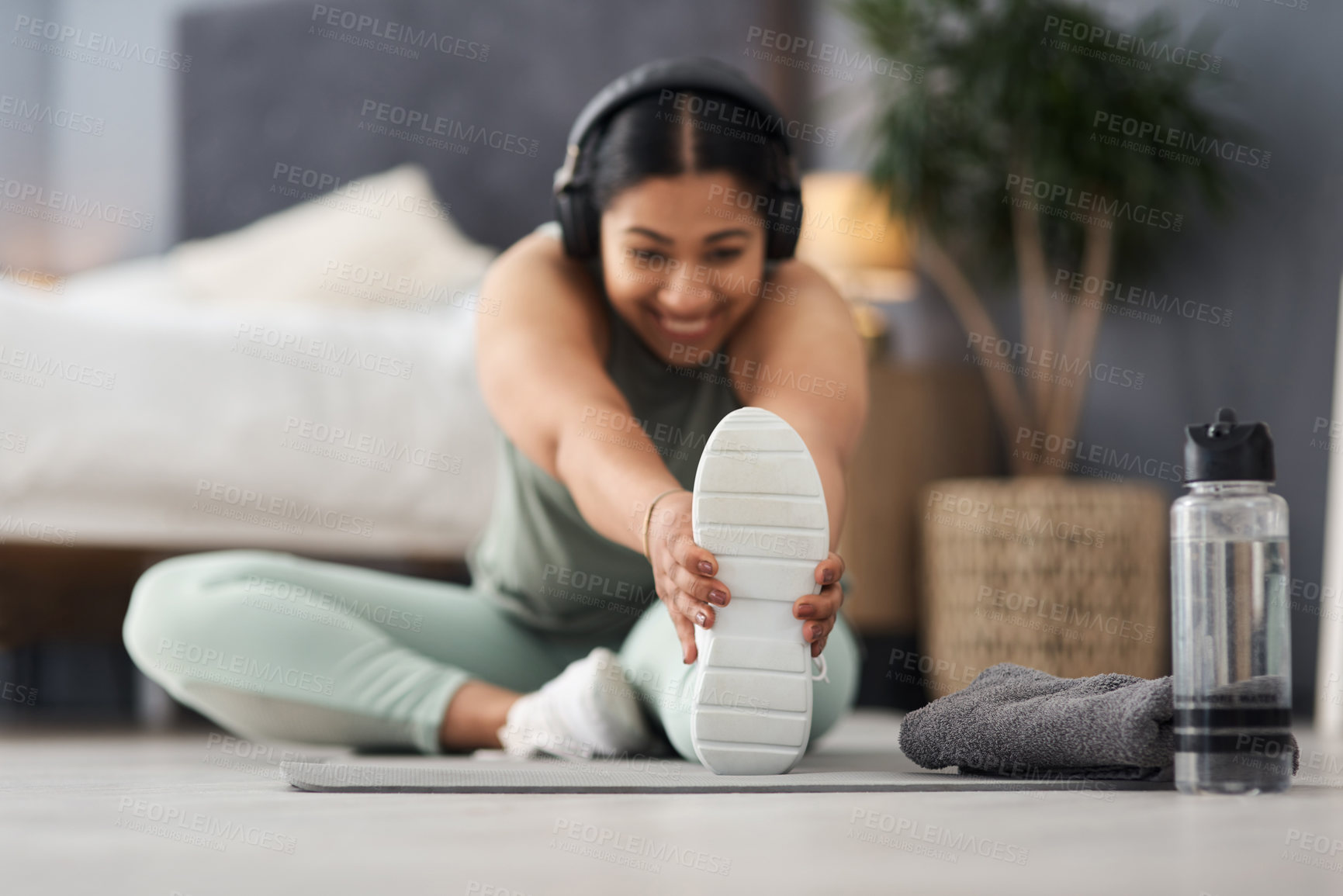 Buy stock photo Shot of a sporty young woman stretching her legs while exercising at home