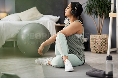 Buy stock photo Shot of a sporty young woman listening to music while exercising at home