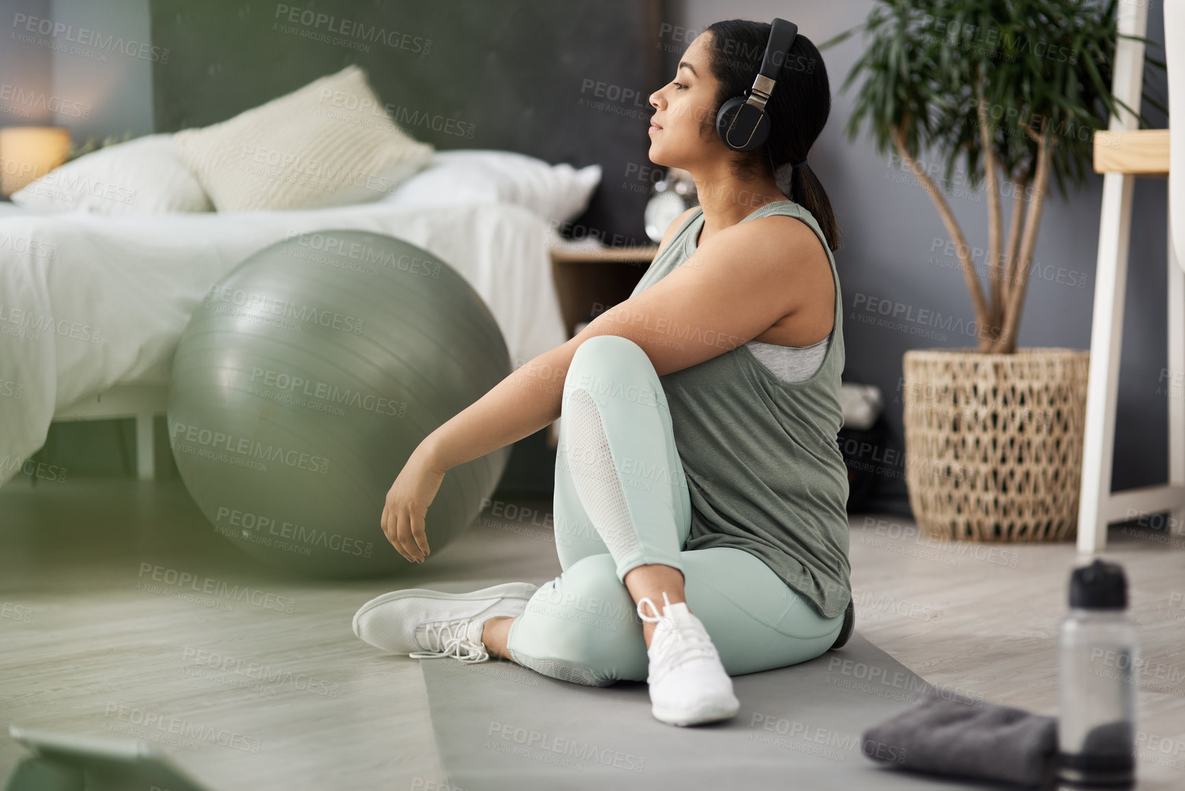 Buy stock photo Shot of a sporty young woman listening to music while exercising at home