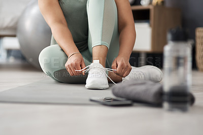 Buy stock photo Closeup shot of an unrecognisable woman tying her shoelaces while exercising at home