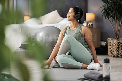 Buy stock photo Shot of a sporty young woman listening to music while exercising at home