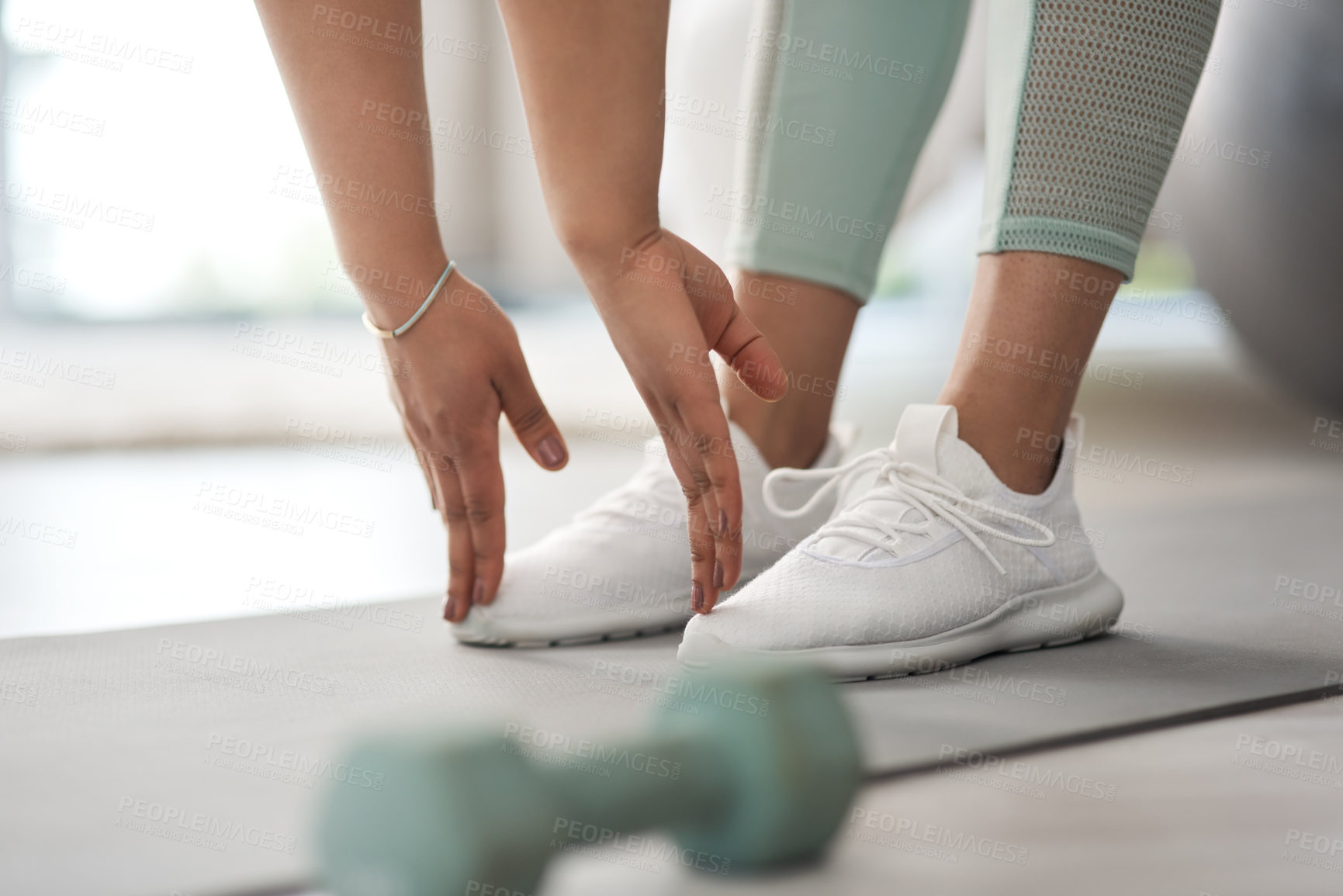 Buy stock photo Closeup shot of an unrecognisable woman stretching to touch her toes while exercising at home