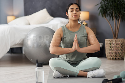 Buy stock photo Shot of a sporty young woman meditating at home