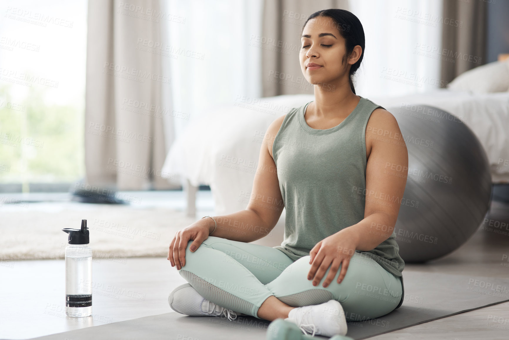 Buy stock photo Shot of a sporty young woman meditating at home