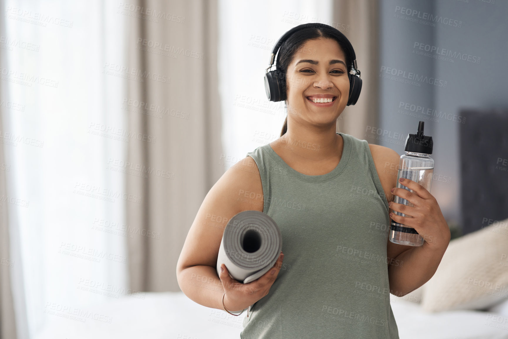 Buy stock photo Portrait of a sporty young woman carrying a mat and water bottle while exercising at home