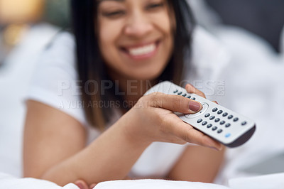 Buy stock photo Shot of a young woman watching television from the comfort of her warm bed