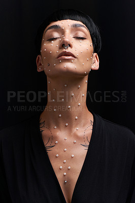 Buy stock photo Studio shot of a beautiful young woman with pearls on her face posing against a black background