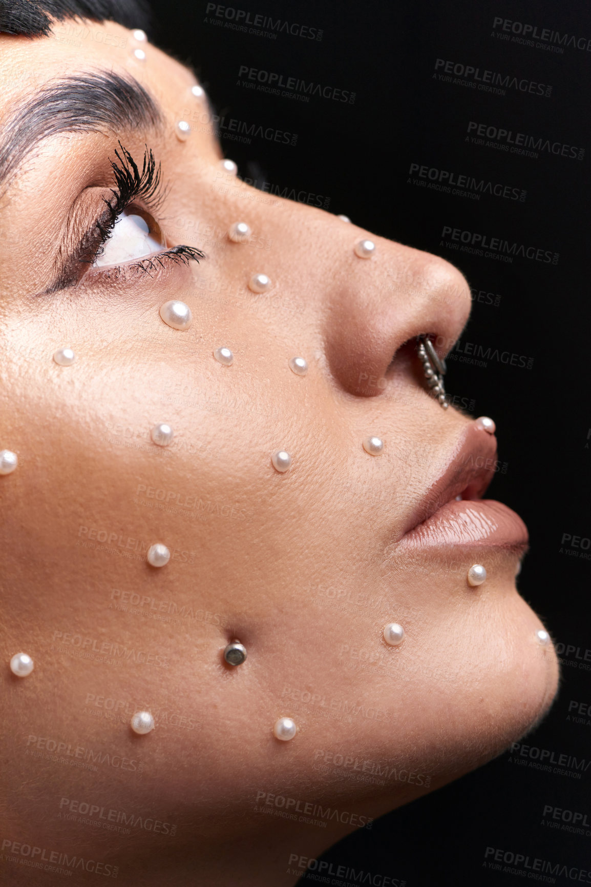 Buy stock photo Studio shot of a beautiful young woman with pearls on her face posing against a black background