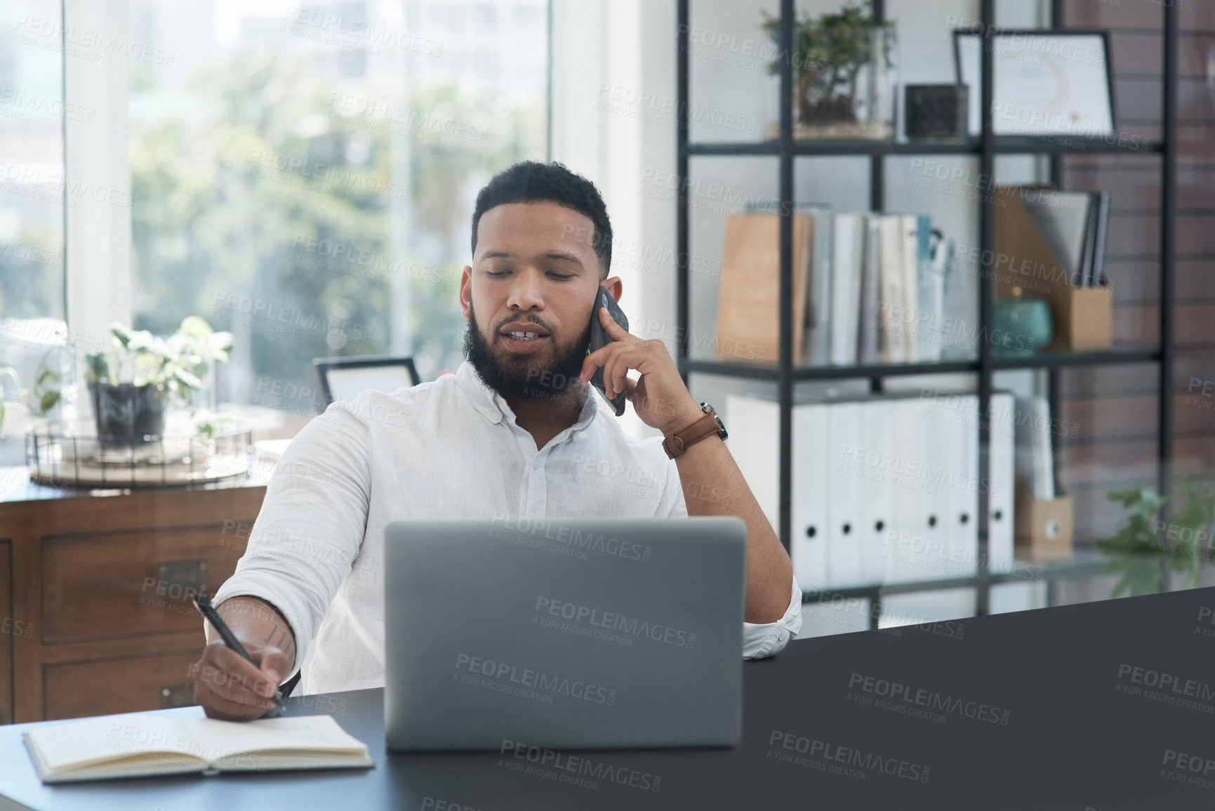 Buy stock photo Laptop, phone call and notebook with a business man at his desk in the office for communication or networking. Computer, mobile and writing with a male employee working online for company negotiation
