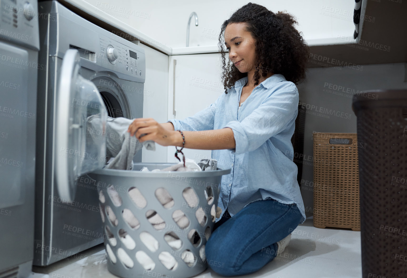 Buy stock photo Shot of a young woman preparing to wash a load of laundry at home