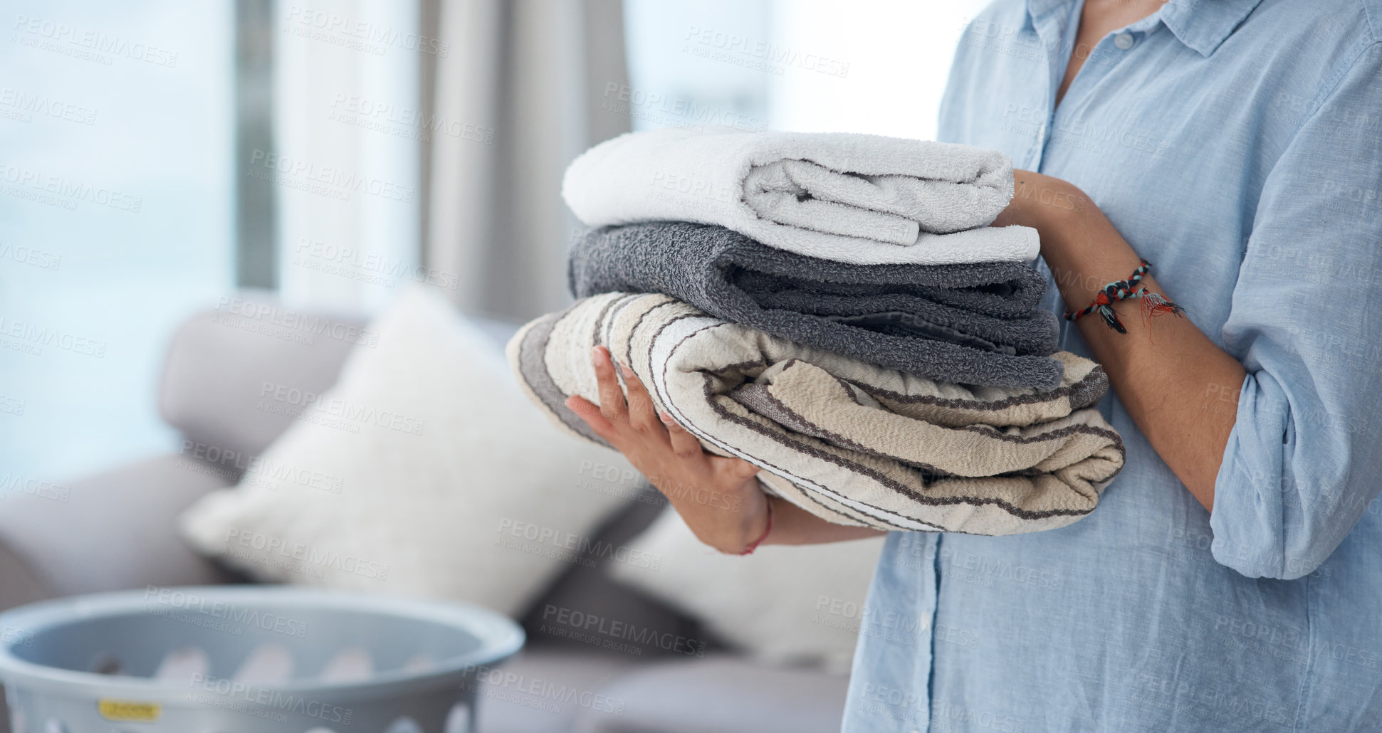 Buy stock photo Hands, laundry and spring cleaning with a woman holding a pile of fresh towels in the living room of her home. Fabric, hospitality and washing with a female cleaner in her apartment for housework