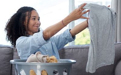 Buy stock photo Shot of a young woman folding away her freshly cleaned laundry at home