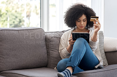 Buy stock photo Shot of a young woman shopping online while sitting on the couch at home