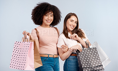 Buy stock photo Studio portrait of two young women carrying a bunch of shopping bags