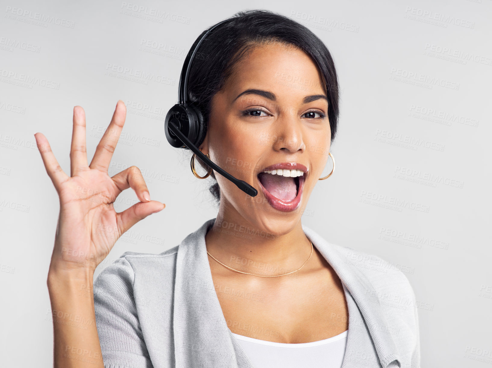Buy stock photo Studio shot of a young businesswoman using a headset and showing an okay sign against a grey background