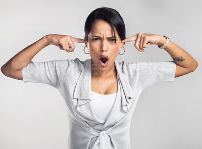 Buy stock photo Studio shot of a young businesswoman covering her ears and looking irritated against a grey background